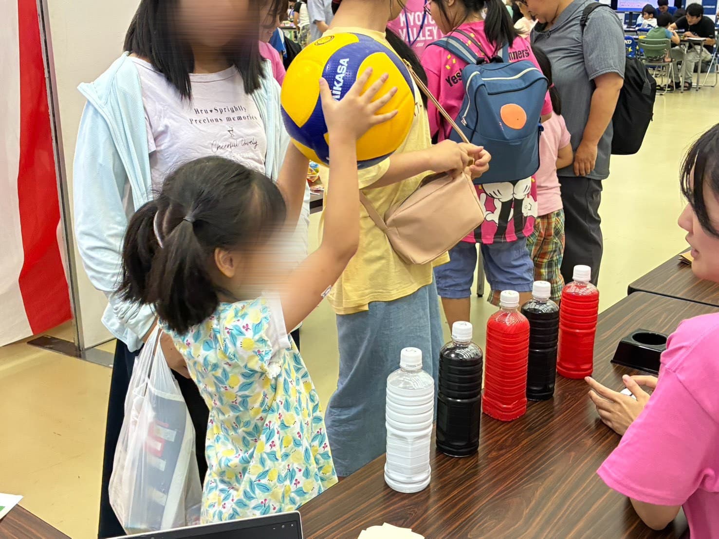 「重さ当てチャレンジ」に挑戦する参加者。まずはボールの重さを確かめます。